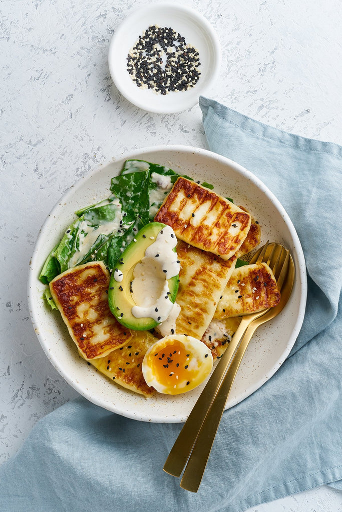 Grilled Sahara Haloumi Cheese with eggs, avocado and green salad in a bowl.